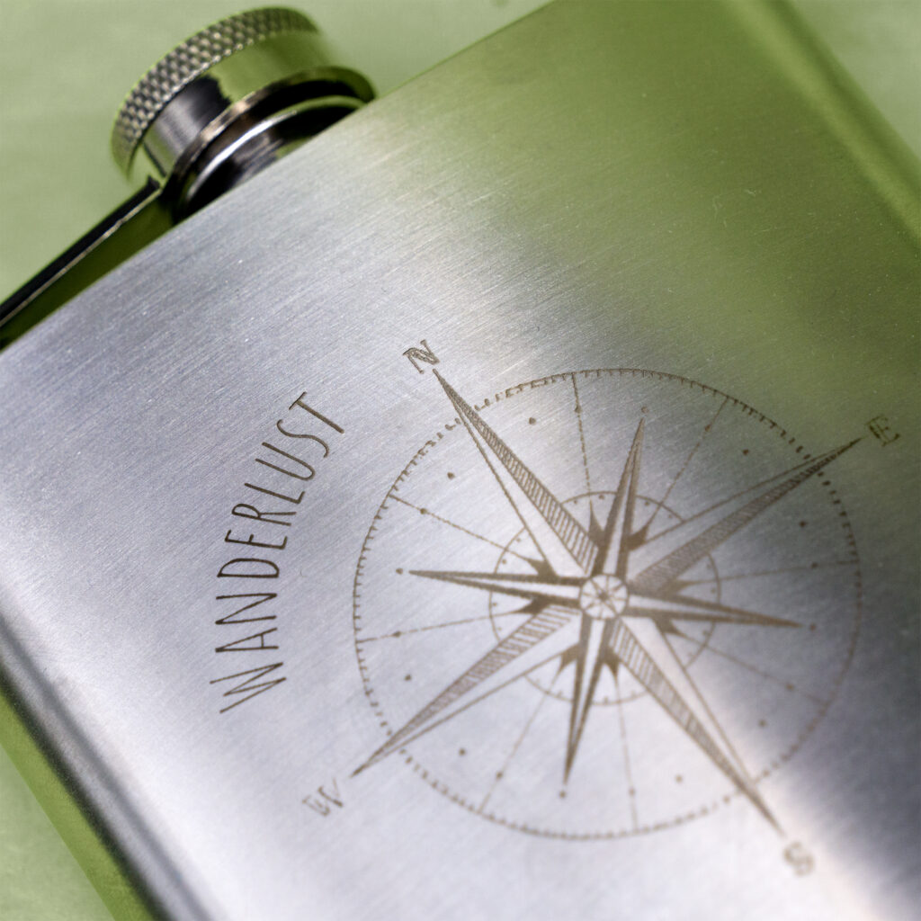 Nahaufnahme von Flachmann mit Lasergravur "Wanderlust" und Kompass