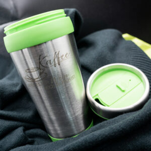 Abbildung Kaffeebecher mit grünen Details und fertigem Motiv "Kaffee – weil es für Wein noch zu früh ist", Deckel nebenliegend zur Ansicht